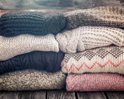 knitted warm cozy sweaters,on wooden background, concept of heat and warm clothing ,place for text